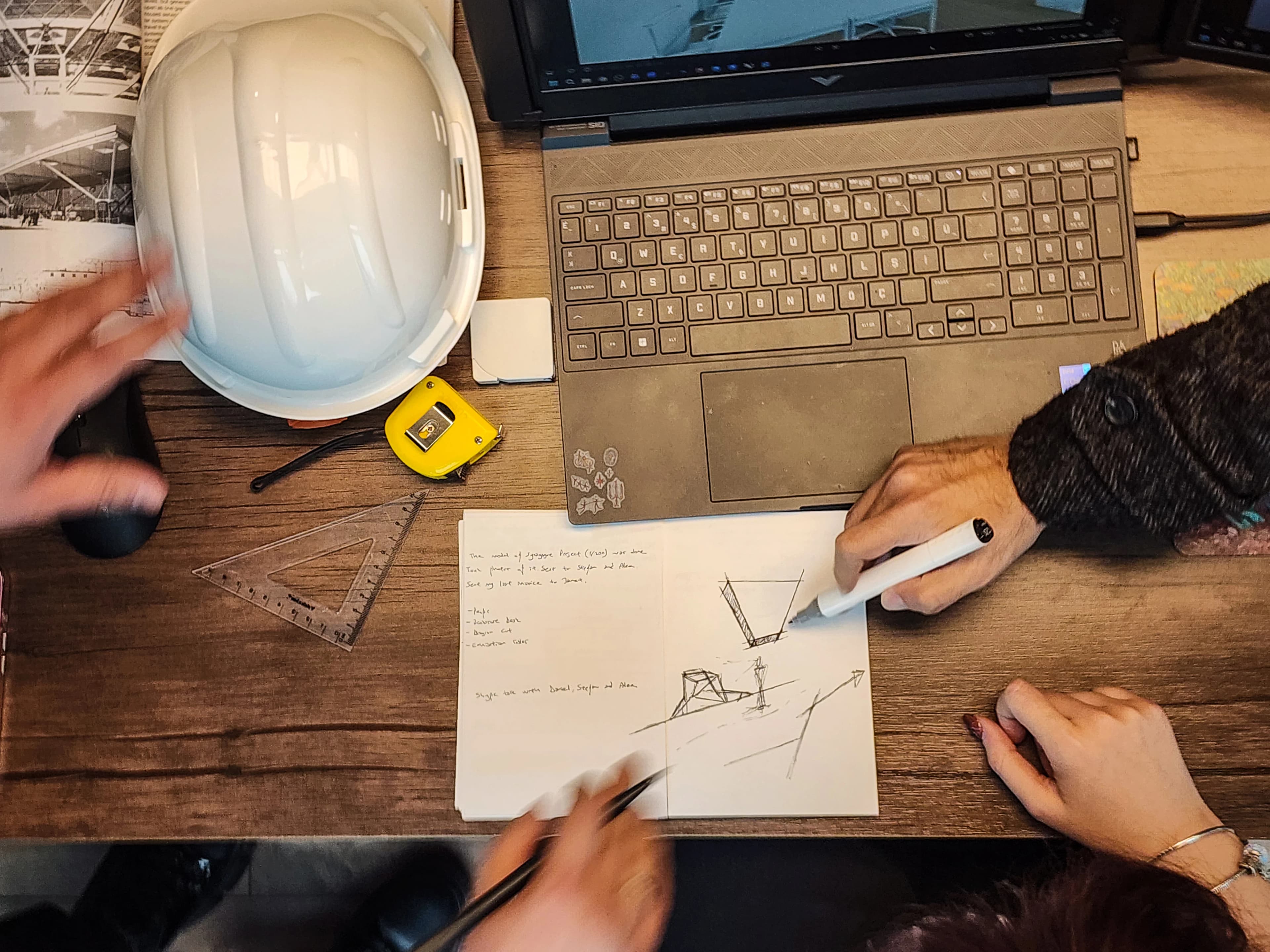 Tasarımcı çift monitör üzerinde iç mekan render incelemesi, masada Coflux baretiyle